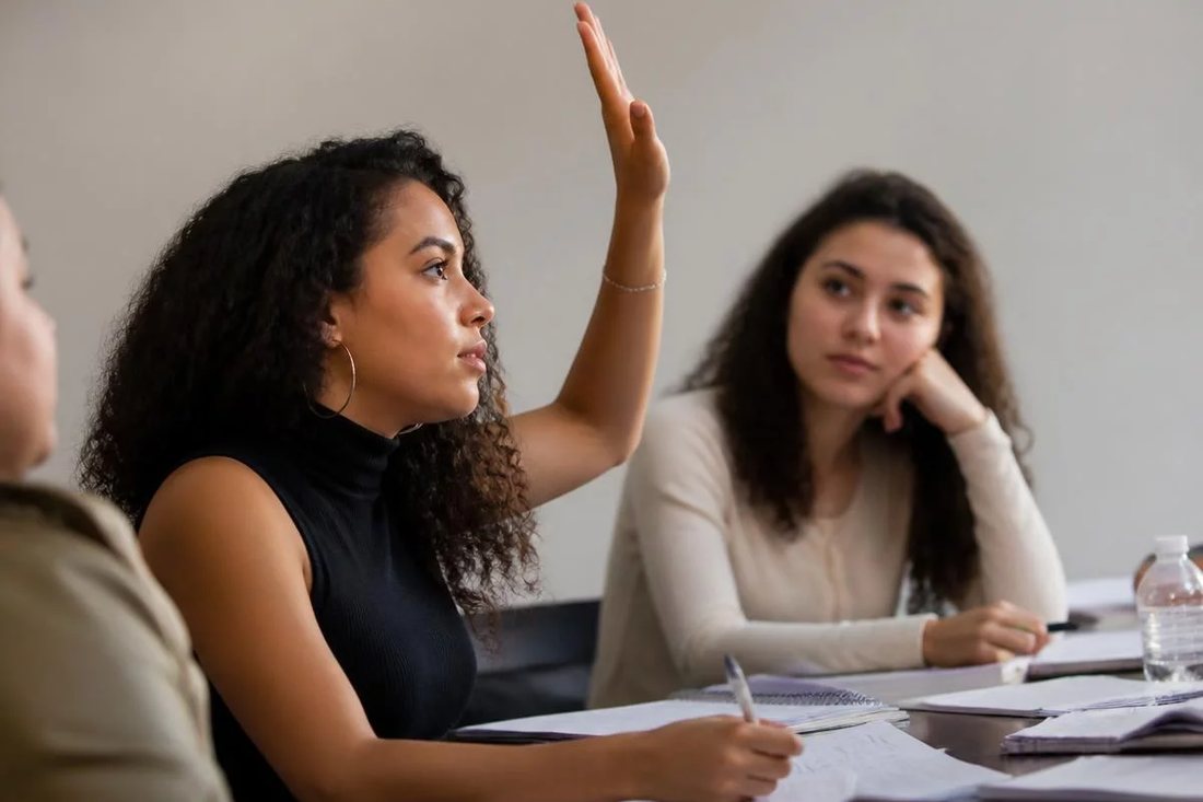 Facilitador em pé apontando para um argumento escrito no quadro durante a sessão